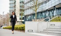 businesswoman-commuting-to-work-talking-on-mobile-phone-outside-modern-office-building-qpam01f65ighsriiafdlj72jk3wtzieqtx4u68iapc